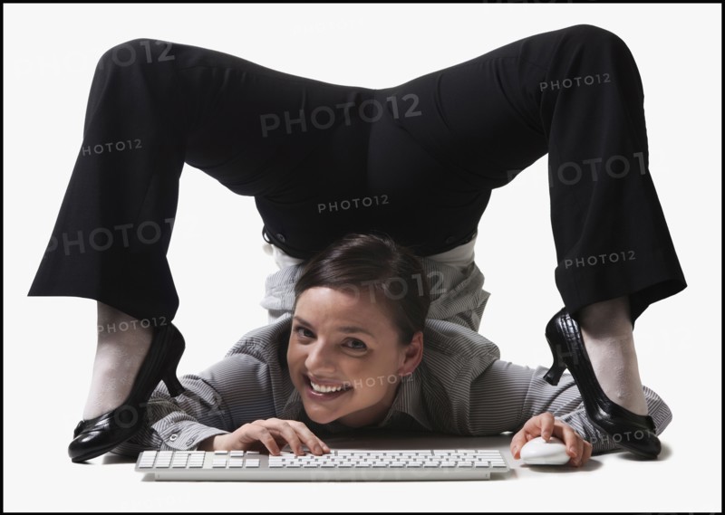Businesswoman contorting her body while typing. Photo : Mike Kemp