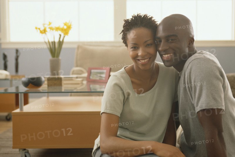 Happy couple sitting together on the floor of their home. Photo : Rob Lewine
