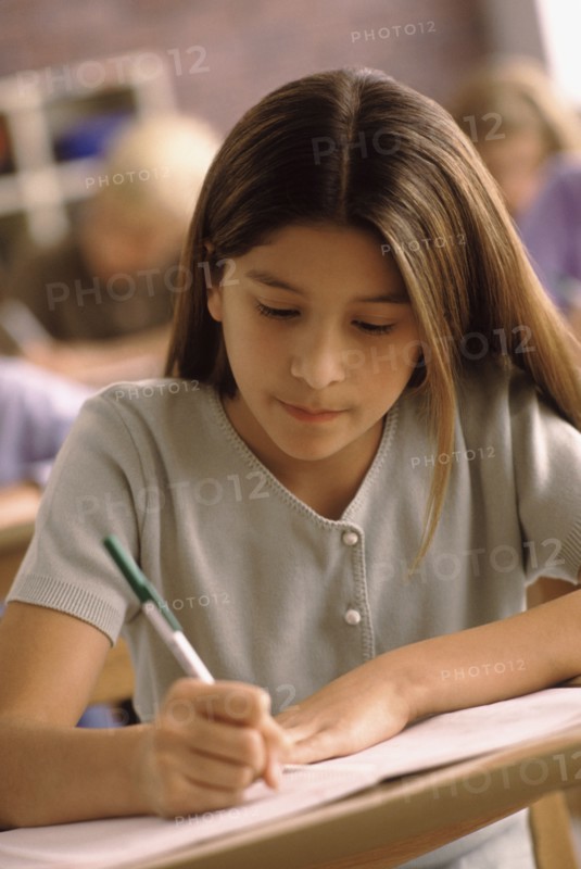 Elementary school student writing at her desk. Photo : Rob Lewine