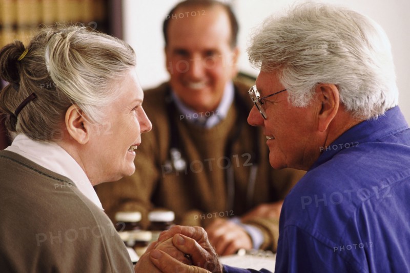 Senior couple sitting at desk across from doctor. Photo : Rob Lewine