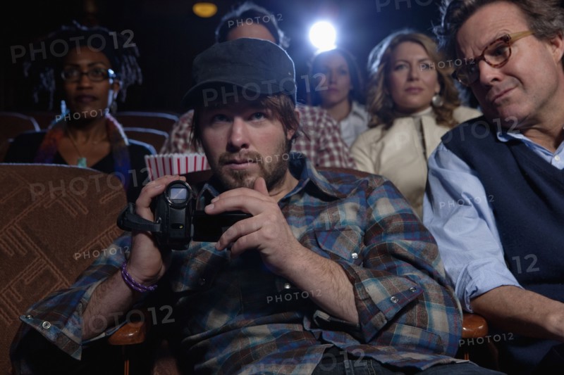 Man using video recorder in movie theatre. Photo : Dan Bannister