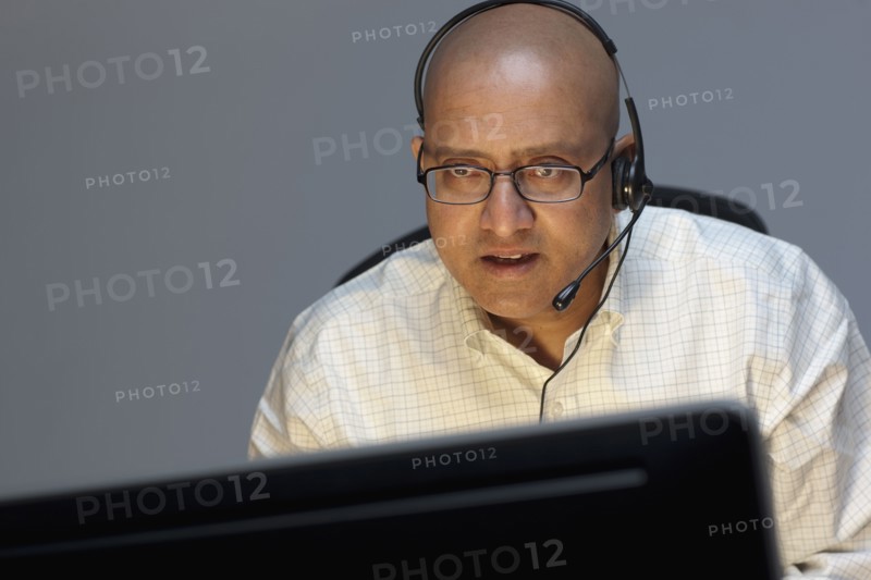 Man wearing headset working on computer. Photo : Dan Bannister