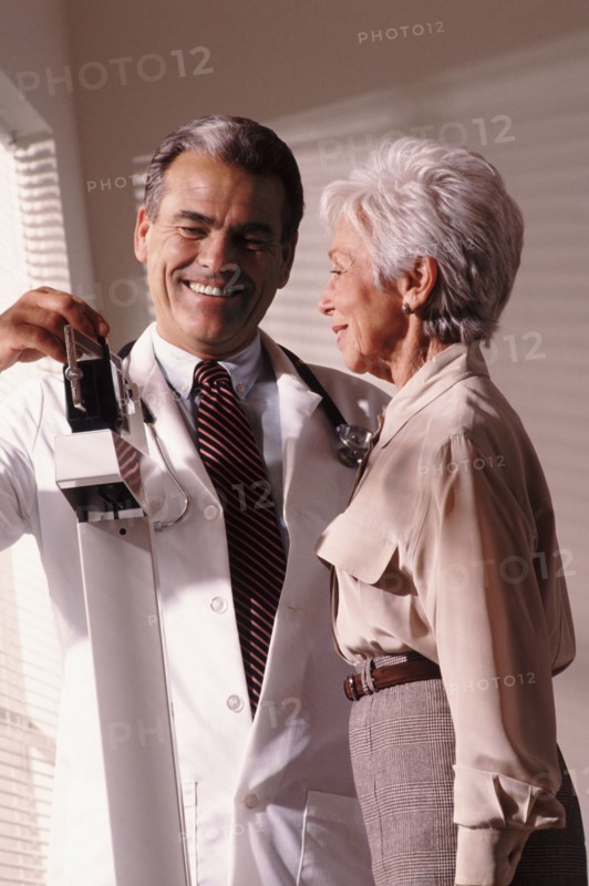 Doctor weighing senior patient. Photo : Rob Lewine