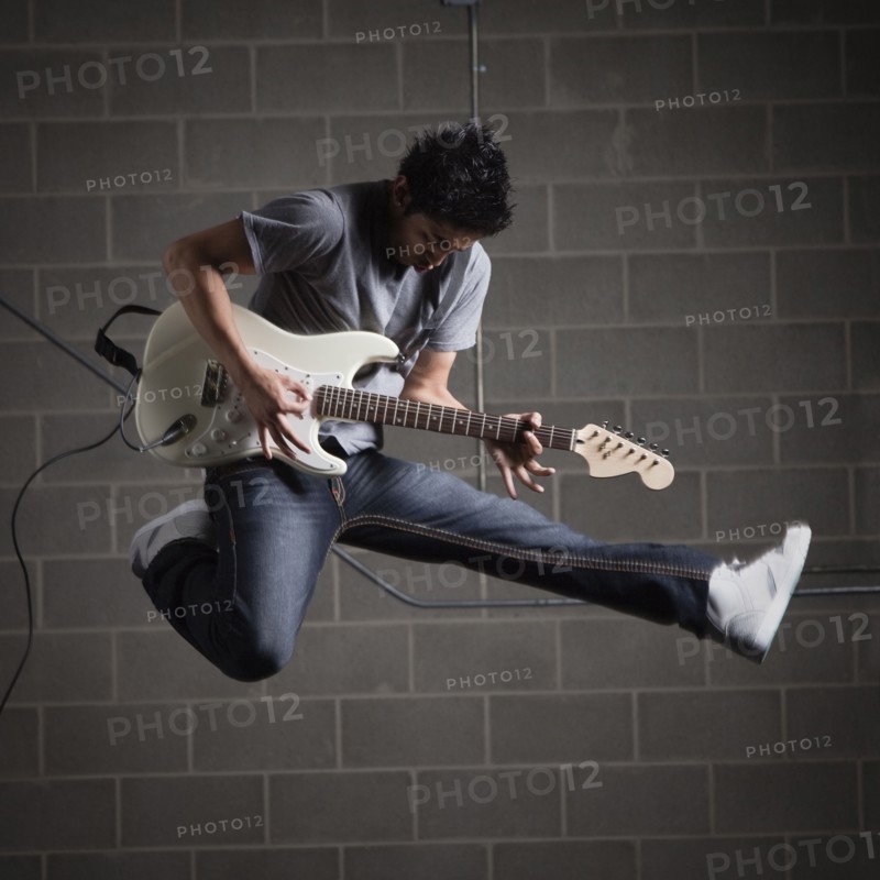 Man jumping in air while playing guitar. Photo : Mike Kemp