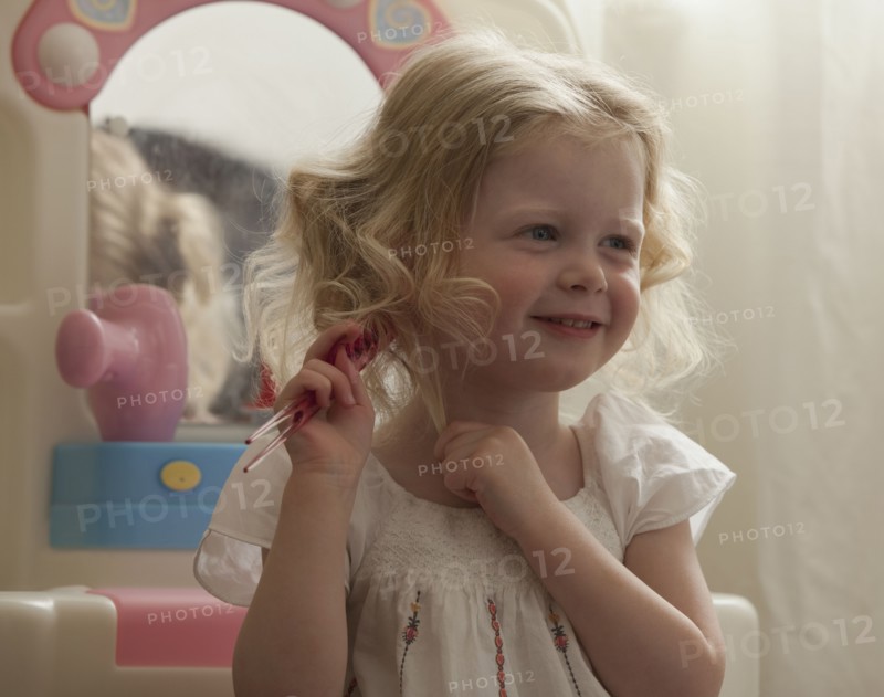 Young girl combing her hair. Photo : Mike Kemp