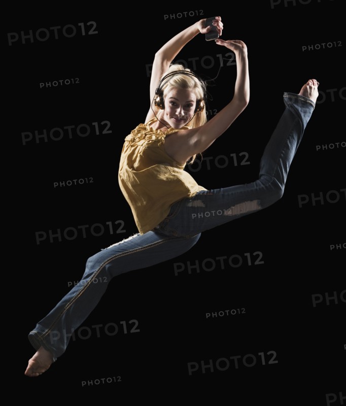Blond woman dancing while listening to music on Mp3 player. Photo : Mike Kemp