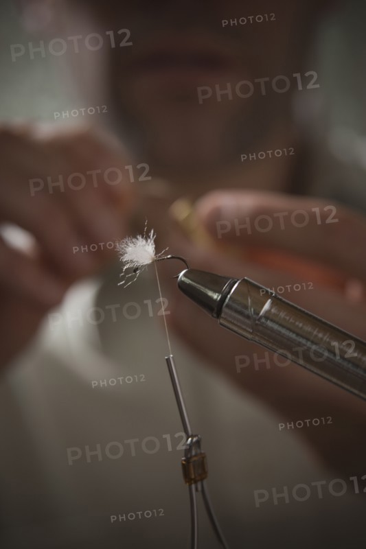 Man repairing fly fishing hook. Photo : Mike Kemp