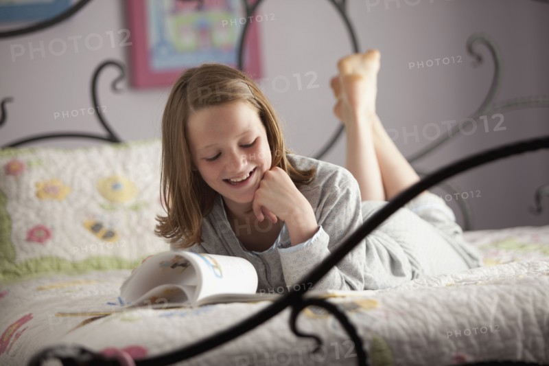 Young girl reading on her bed. Photo : Mike Kemp