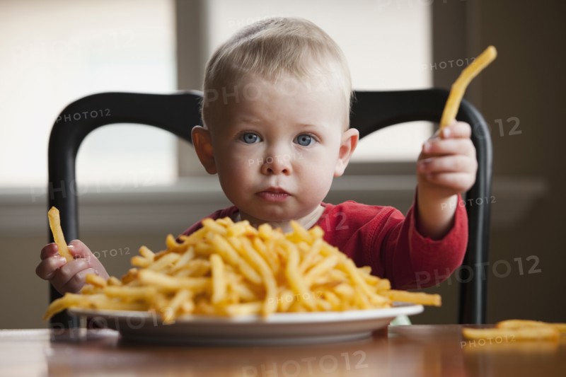 Toddler eating a large plate of French fries. Photo : Mike Kemp