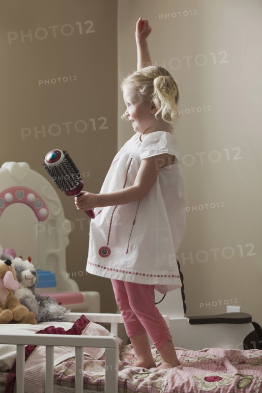 Young girl dancing on her bed. Photo : Mike Kemp