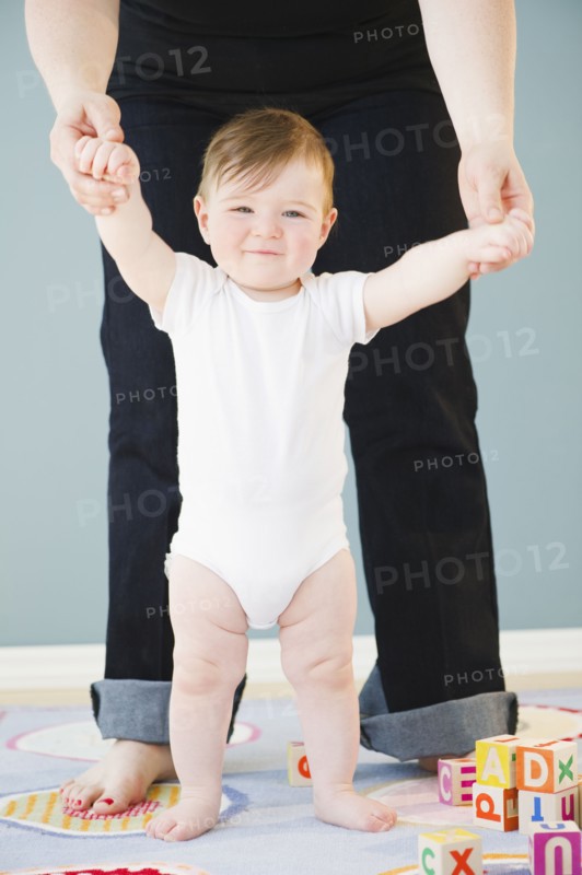 Toddler holding onto mother's hands. Photo : Jamie Grill