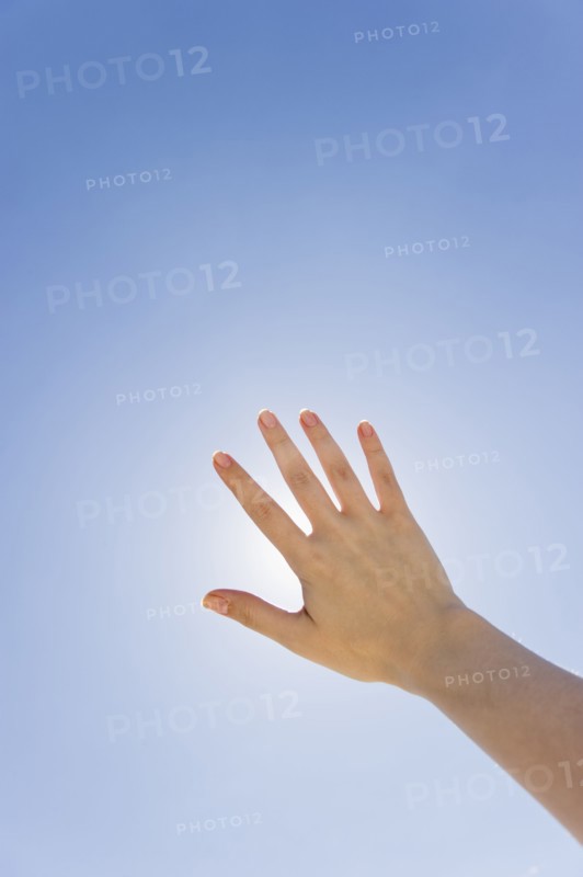 Hand held up in front of sunshine.