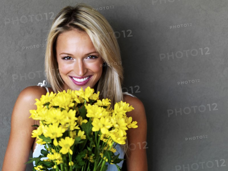 Pretty blond woman holding a bouquet of flowers. Photo : momentimages