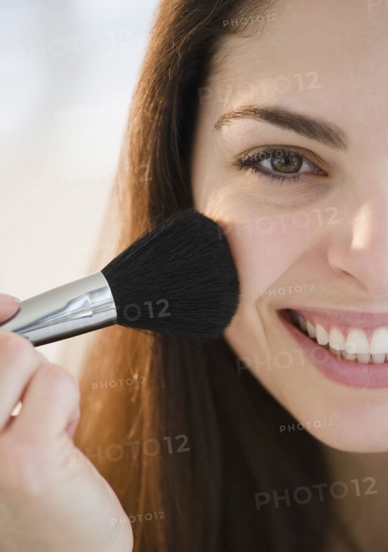 Young woman putting on blush. Photo. Jamie Grill