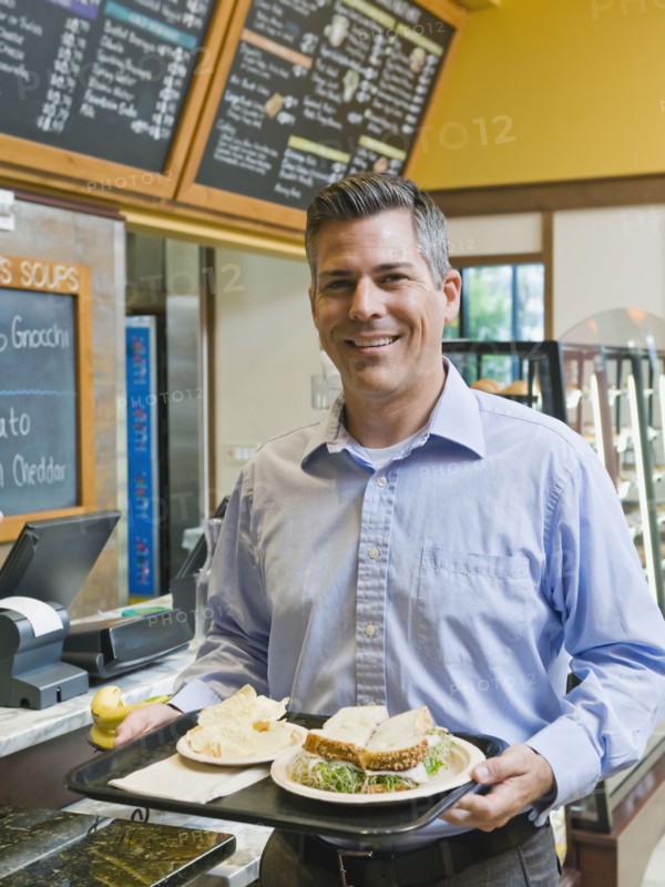 Man carrying sandwich on tray. Photo. Erik Isakson