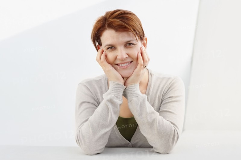 Charming woman sitting at table. Photo : momentimages