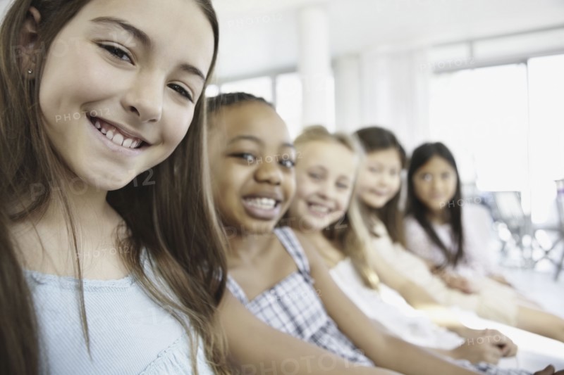 Group of young girls sitting in a row. Photo. momentimages