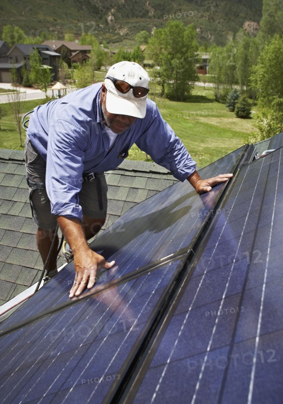 Construction worker installing solar panel on roof. Photo. Shawn O'Connor