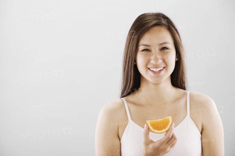 Woman holding a slice of orange. Photo. FBP