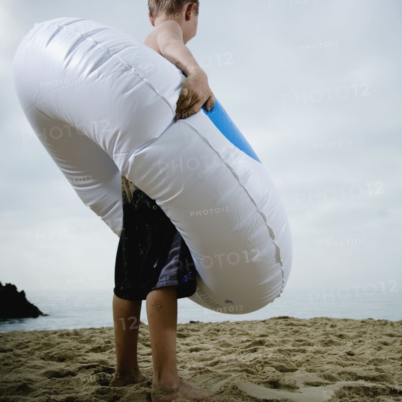 Young boy standing in an inflatable tube at the beach. Photo. FBP