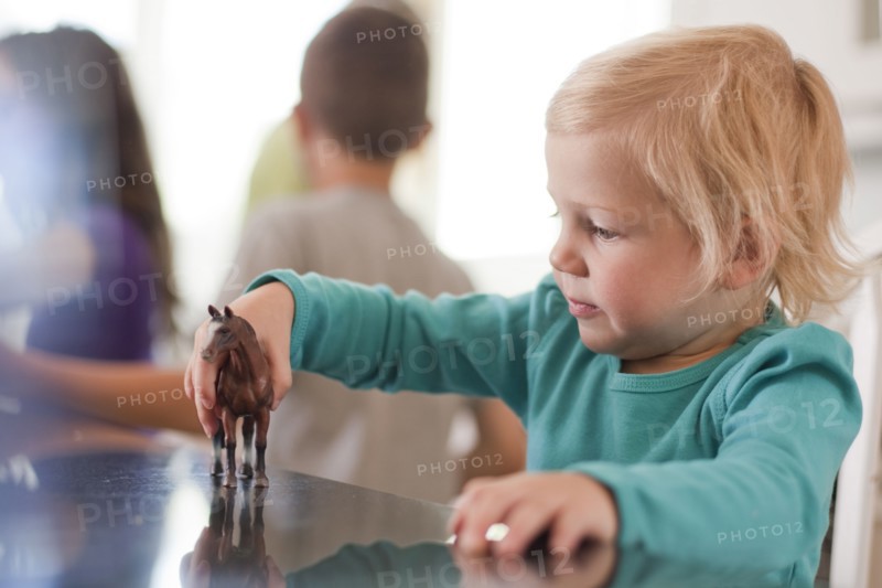 Young girl playing with toy horse. Photo. Tim Pannell