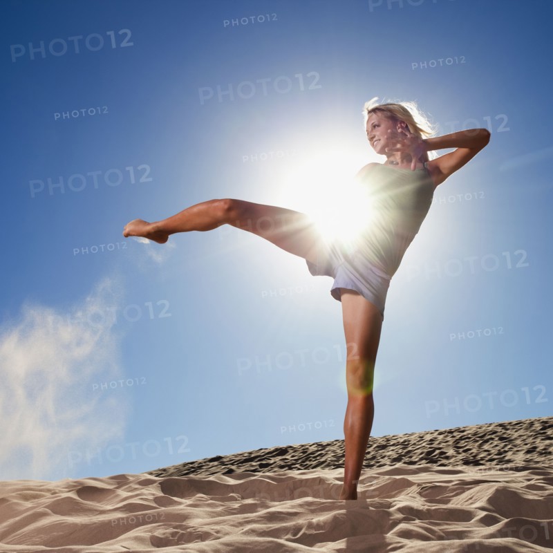 Female dancer kicking her leg on the beach. Photo : Mike Kemp