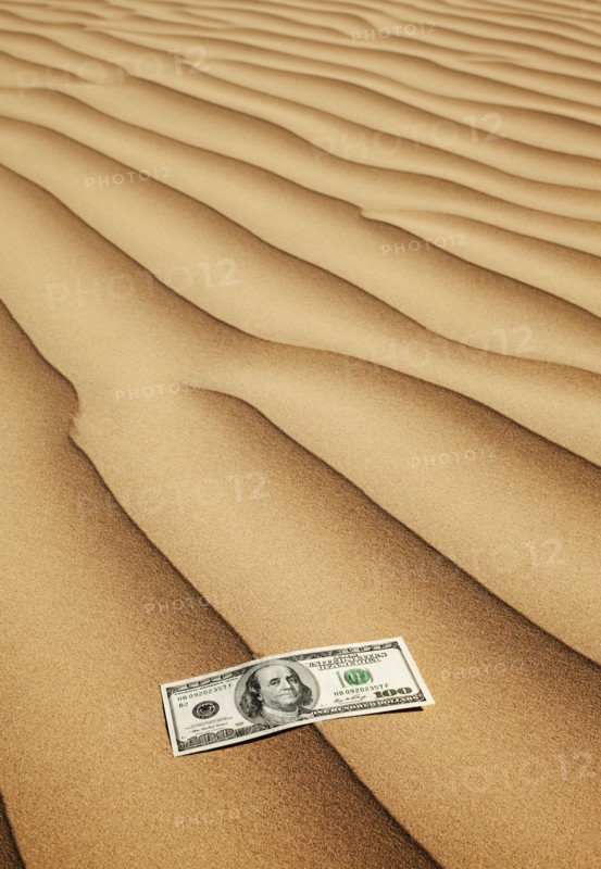 100 dollar bill on sand in desert. Photo. Mike Kemp
