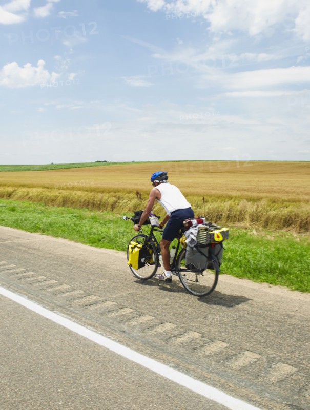 Adventure cyclist biking on rural road. Photo. John Kelly