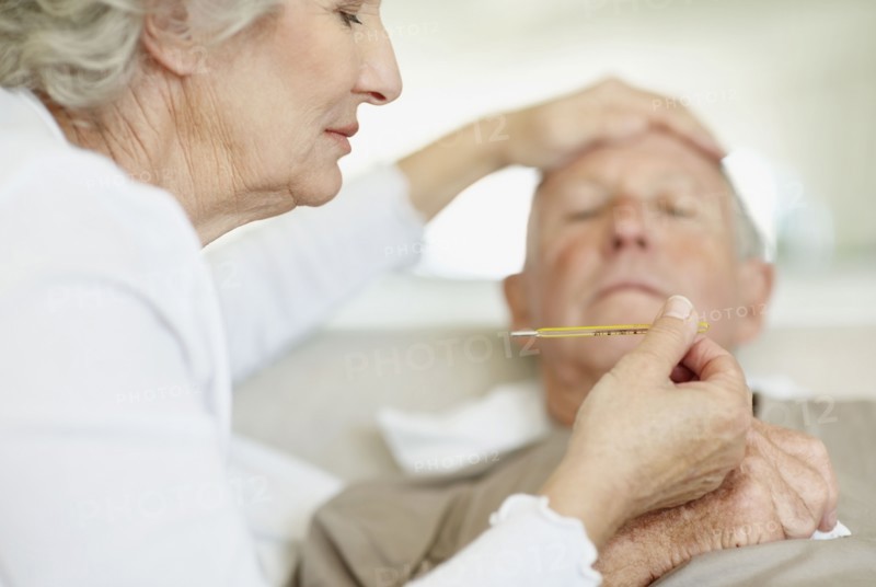 Senior woman caring for man with a fever. Photo. momentimages