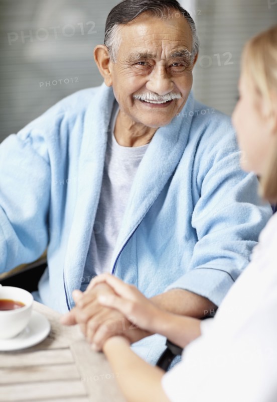 Nurse and senior patient sitting at table. Photo. momentimages