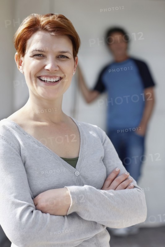 Cheerful woman standing with her arms crossed. Photo. momentimages