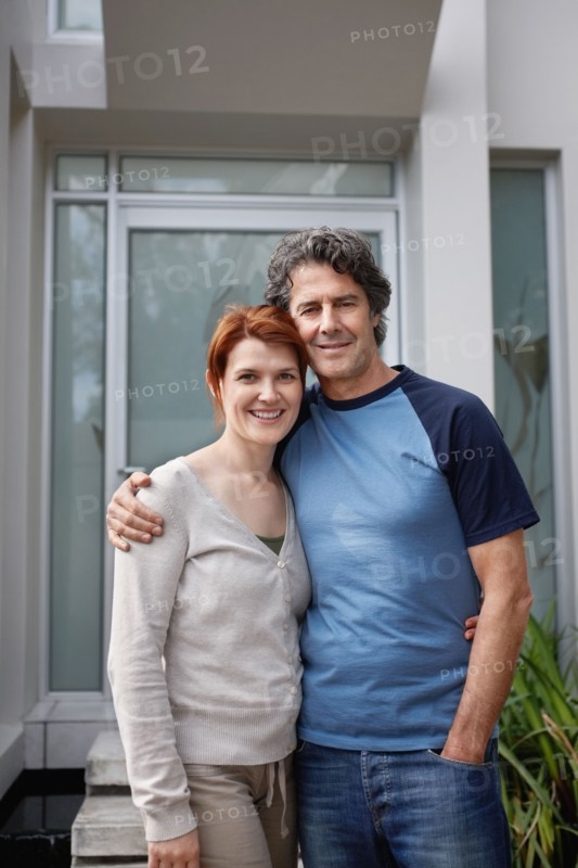 Happy couple standing with their arms around one another. Photo. momentimages