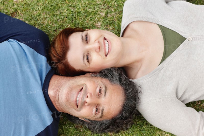 Happy couple relaxing on the grass together. Photo : momentimages