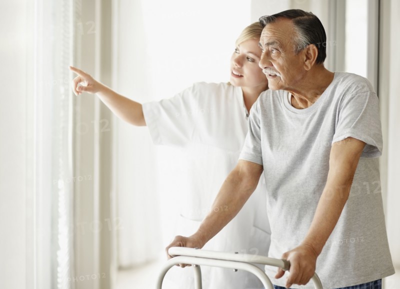 Nurse assisting patient with a walker. Photo : momentimages