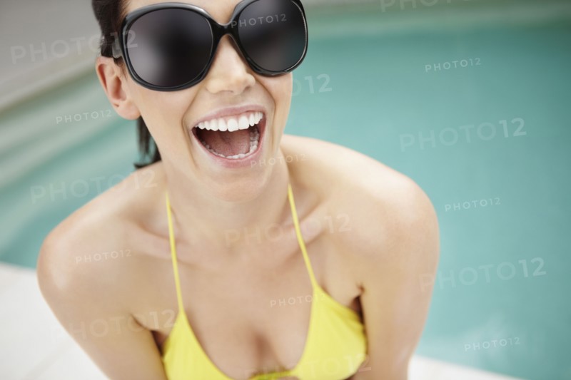 Laughing woman wearing bikini and sunglasses. Photo. momentimages