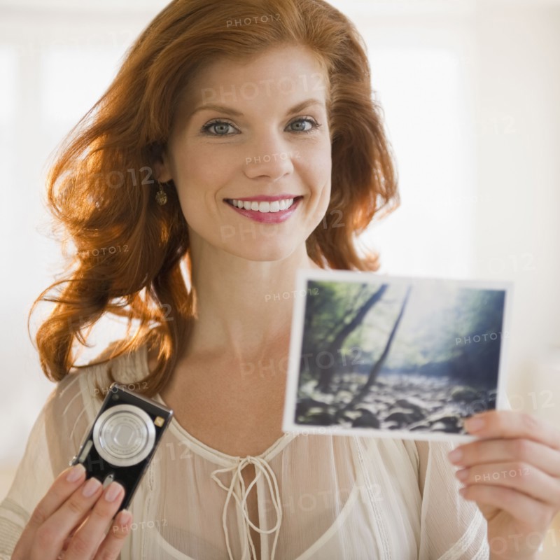 Woman holding camera and photograph. Photo : Jamie Grill