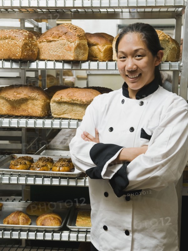 Chef standing beside trays of freshly baked goods. Photo. Erik Isakson