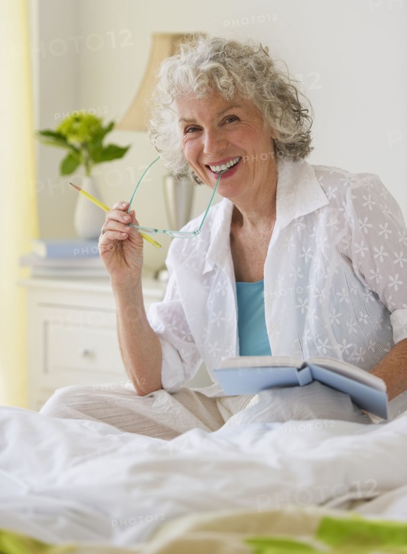 Woman reading a book in bedroom. Photo. Daniel Grill