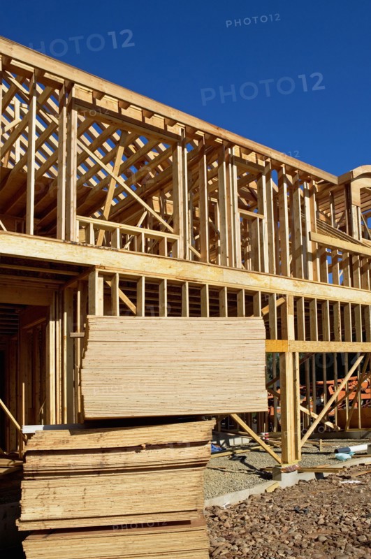Stacks of plywood in front of house frame. Photo. fotog