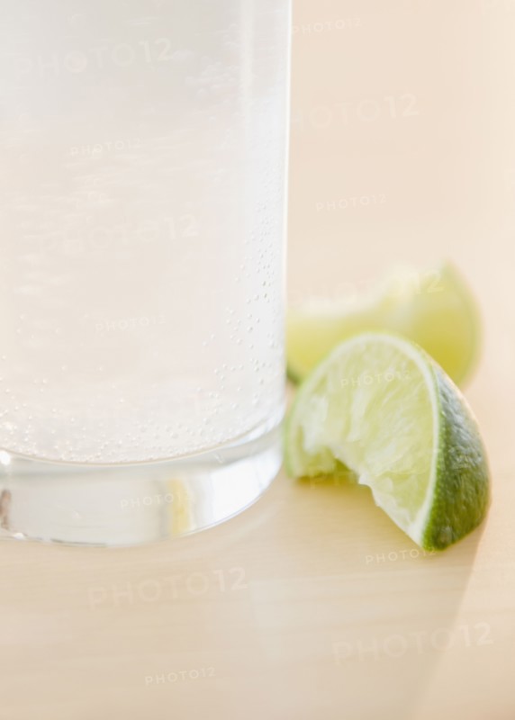 Slices of lime beside glass of water. Photo. Jamie Grill