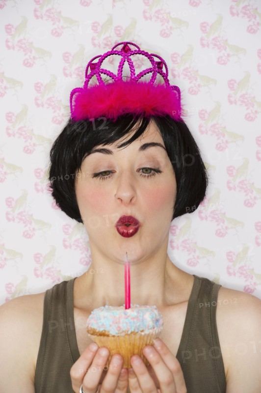 Birthday girl blowing out candle on cupcake. Photo : Daniel Grill