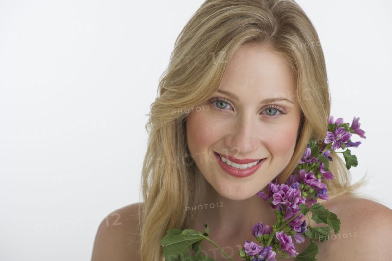 Blond woman holding purple flowers.