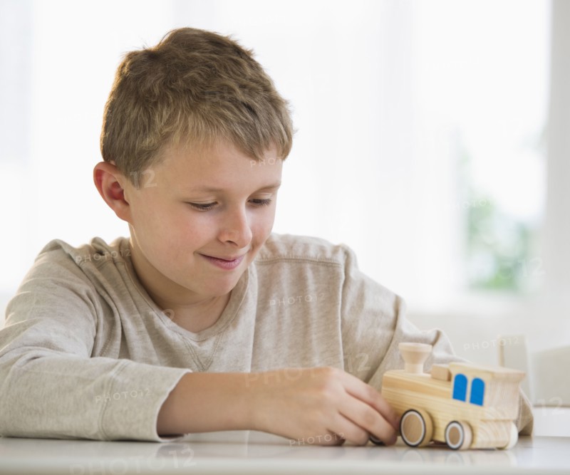Young boy looking at wooden train.