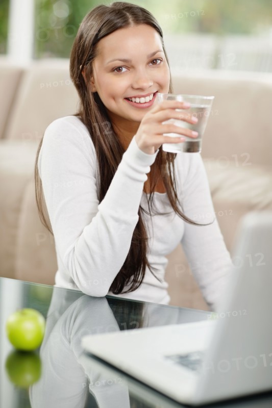 Woman drinking water while browsing the internet. Photo. momentimages