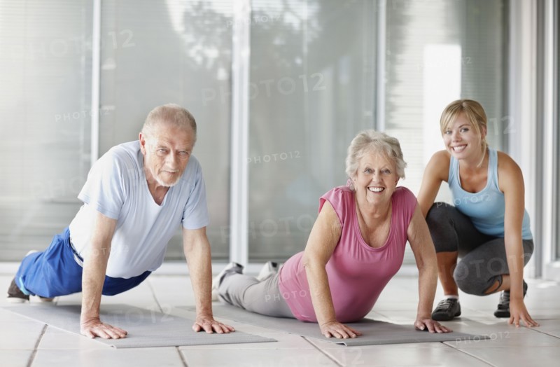 Senior couple exercising with a fitness instructor. Photo. momentimages