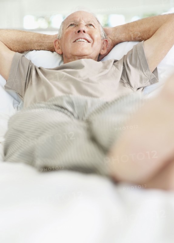 Relaxed senior man lying on bed. Photo. momentimages