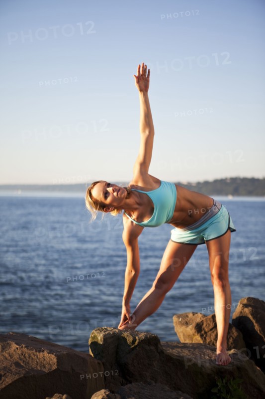 Athletic woman stretching by the ocean. Photo. Take A Pix Media