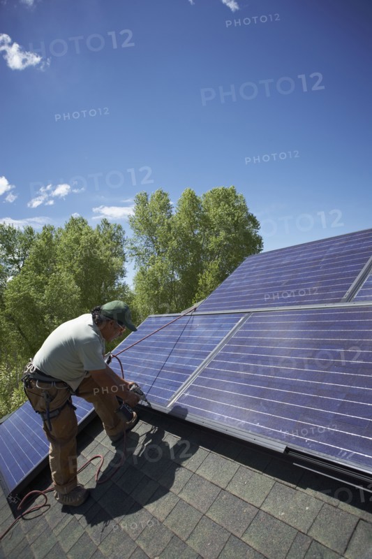 Construction worker installing solar panel on roof. Photo. Shawn O'Connor