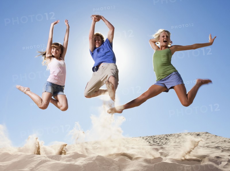 Three people jumping in the sand. Photo. Mike Kemp
