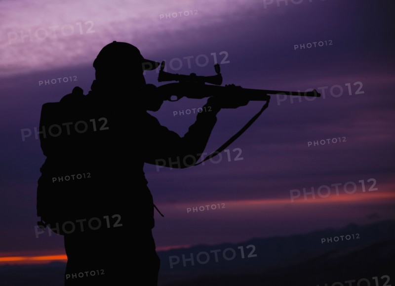 Hunter looking through scope of rifle. Photo. Mike Kemp